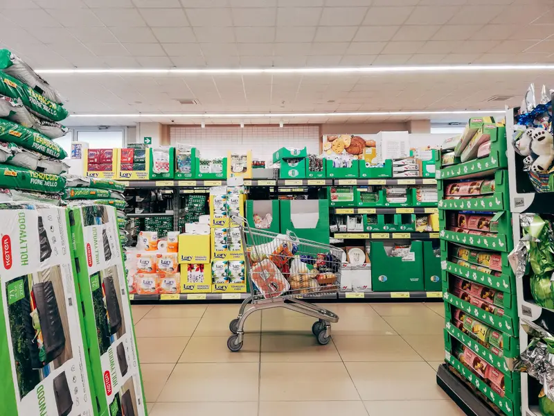 Prolaz između polica s robom i kolica za kupovinu